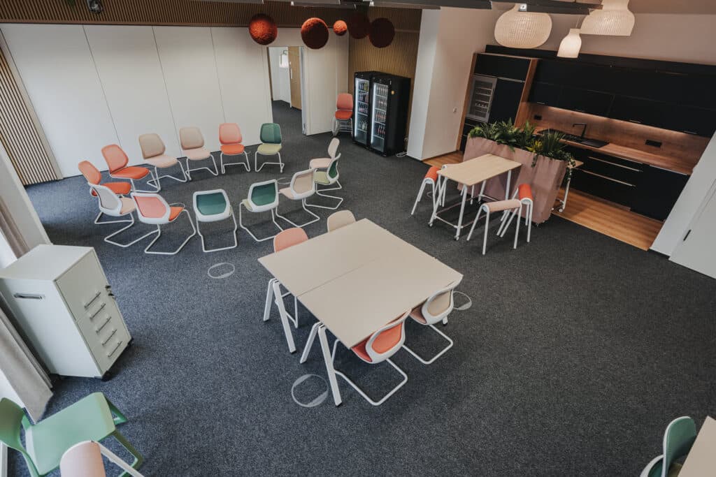 Moderner Besprechungsraum mit farbigen Stühlen und Tischen.