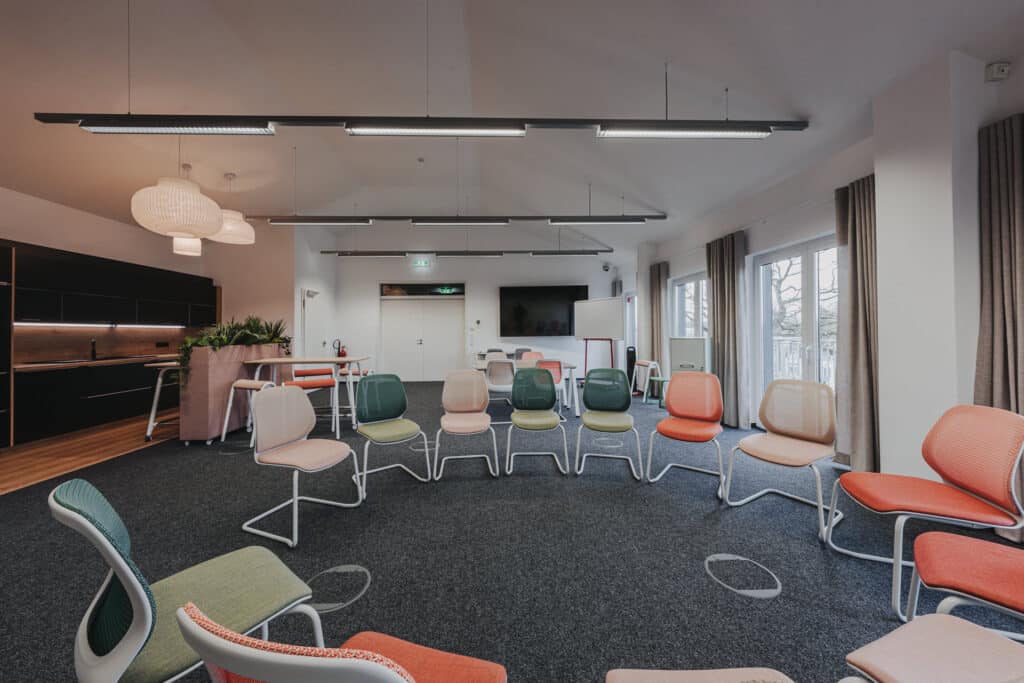 Moderner Konferenzraum mit Stuhlkreis und Präsentationstechnik.