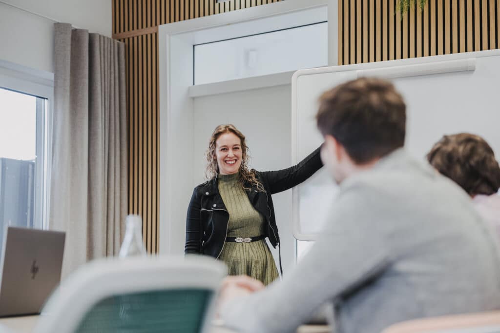 Frau präsentiert vor Kollegen im Konferenzraum.