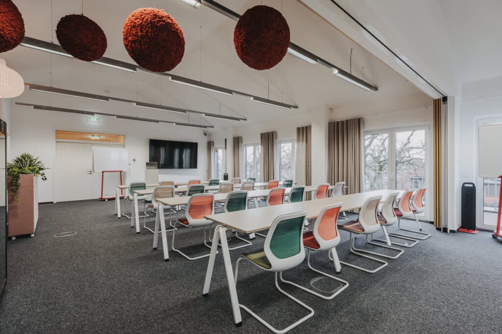 Konferenzraum mit modernen Stühlen und großem Bildschirm.